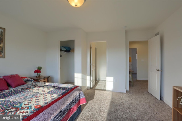 carpeted bedroom with a walk in closet and a closet