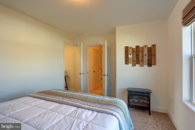 bedroom featuring a wood stove, multiple windows, and carpet flooring