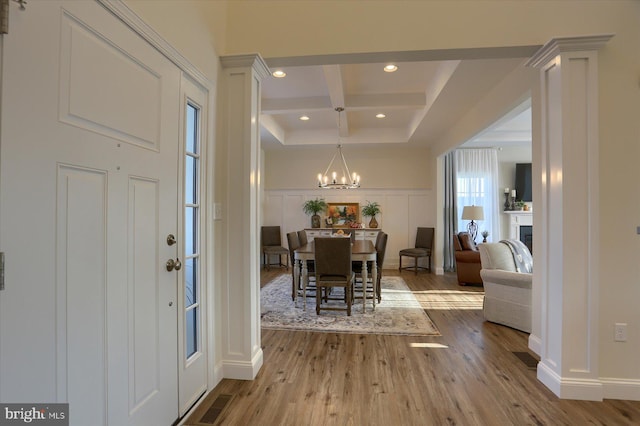 entrance foyer featuring light hardwood / wood-style floors, an inviting chandelier, beam ceiling, and coffered ceiling