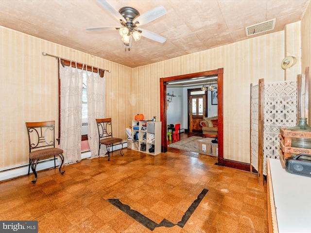 sitting room with ceiling fan, a wealth of natural light, and a baseboard heating unit