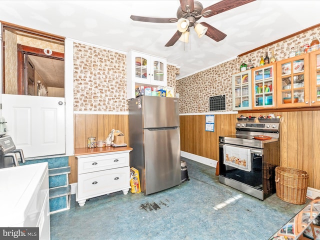 kitchen featuring wooden walls, appliances with stainless steel finishes, white cabinets, and ceiling fan