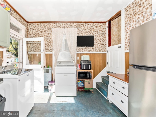 clothes washing area featuring independent washer and dryer, crown molding, and wooden walls