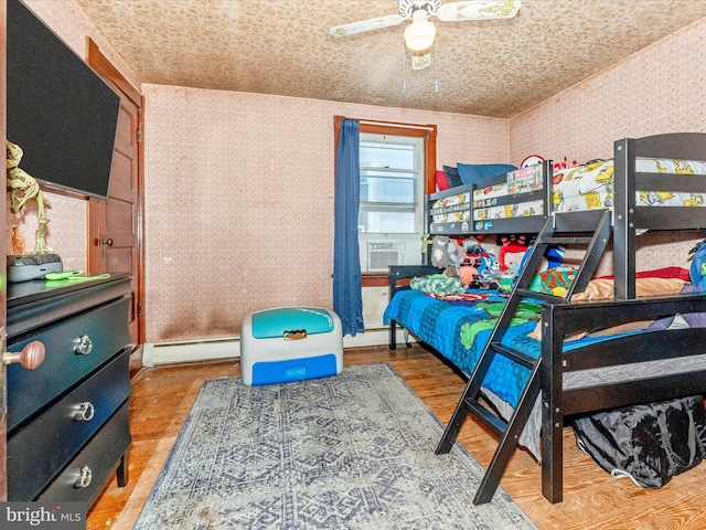 bedroom with ceiling fan, wood-type flooring, a baseboard radiator, and cooling unit