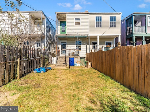 rear view of property featuring a lawn and a balcony