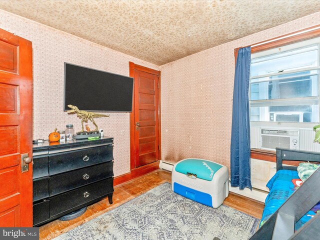 interior space with a baseboard heating unit, cooling unit, and light wood-type flooring