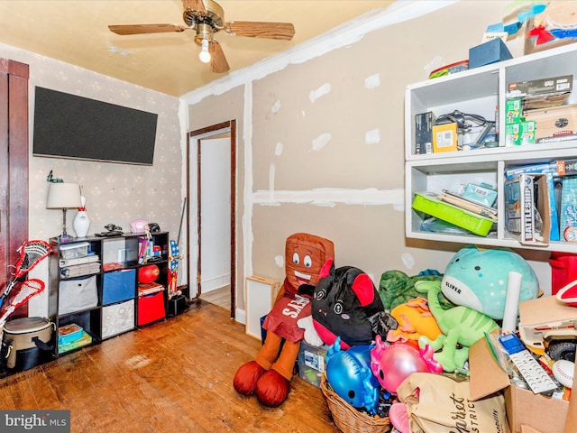 recreation room with ceiling fan, wood-type flooring, and ornamental molding