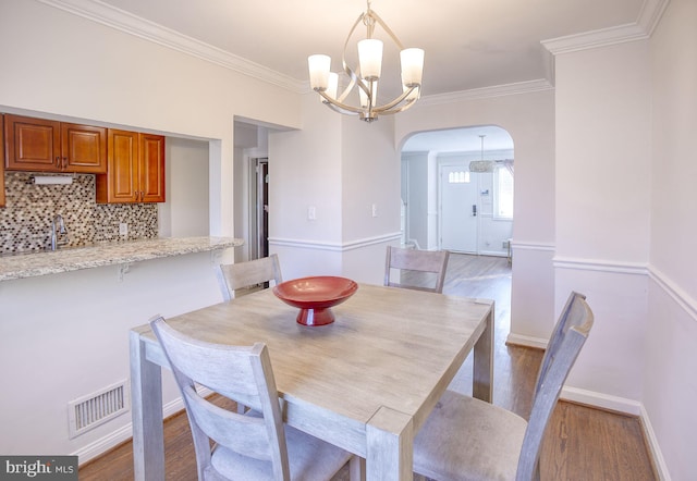 dining space featuring ornamental molding, light wood-type flooring, and a chandelier