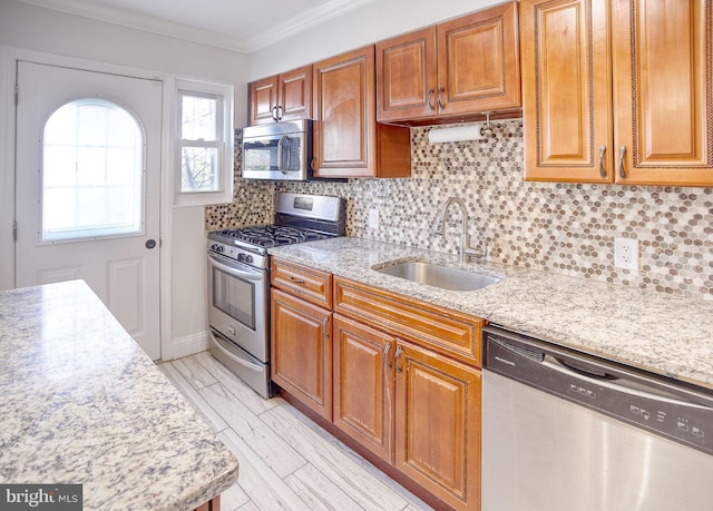 kitchen with crown molding, backsplash, appliances with stainless steel finishes, light stone countertops, and sink