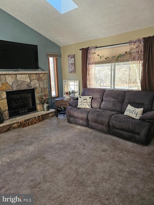 carpeted living room featuring a fireplace, plenty of natural light, a textured ceiling, and vaulted ceiling with skylight