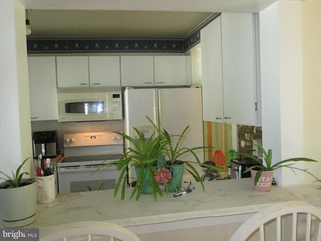 kitchen featuring white cabinetry, light stone counters, and white appliances