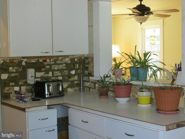 kitchen with white cabinetry, ceiling fan, and backsplash