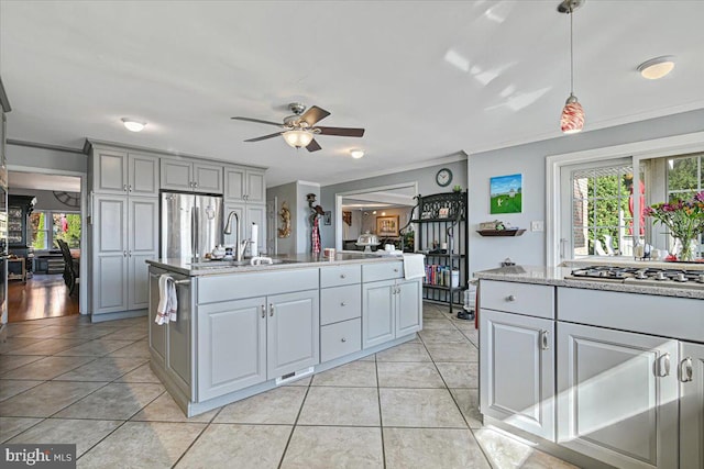 kitchen featuring gray cabinetry, a kitchen island with sink, sink, ornamental molding, and stainless steel appliances