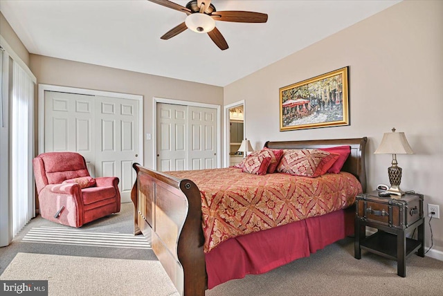 carpeted bedroom with multiple windows, ceiling fan, and two closets