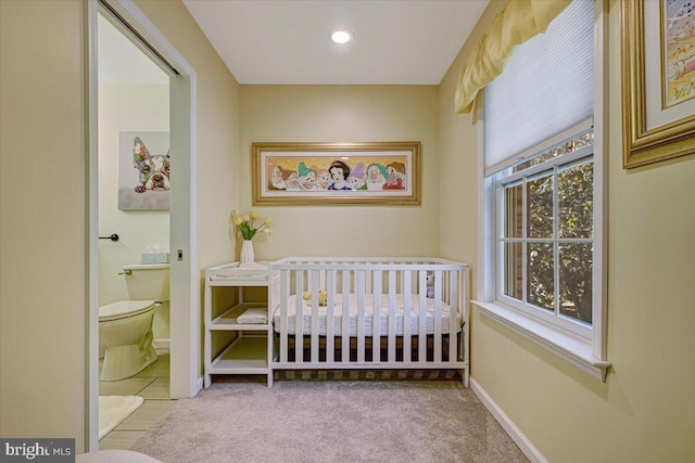 carpeted bedroom with ensuite bath and a nursery area