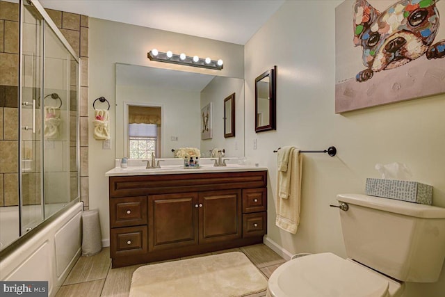 full bathroom with vanity, bath / shower combo with glass door, and toilet