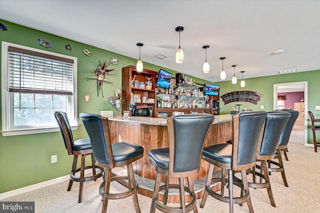 bar featuring decorative light fixtures, light colored carpet, and light stone countertops