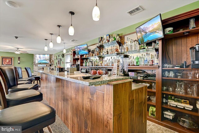 bar with ceiling fan, hanging light fixtures, and light stone counters