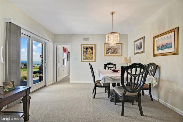 carpeted dining area with a chandelier