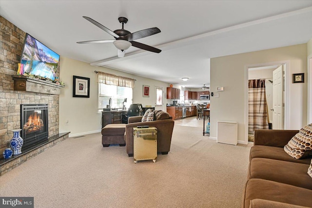 carpeted living room featuring a fireplace and ceiling fan