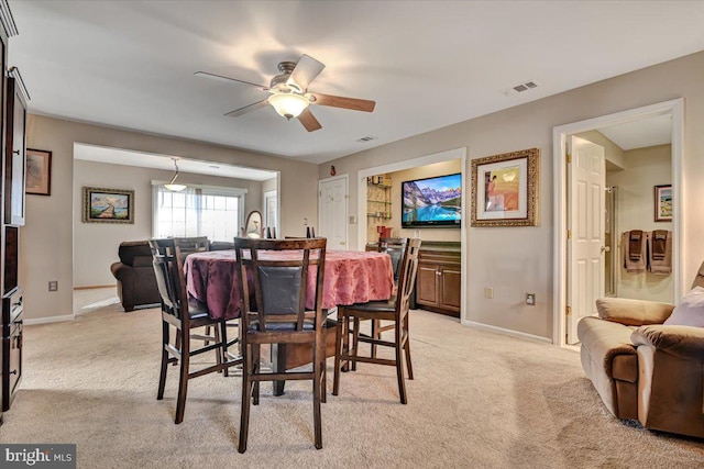 carpeted dining area with ceiling fan