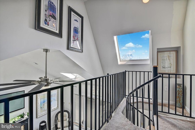 stairway featuring ceiling fan, vaulted ceiling with skylight, and carpet floors