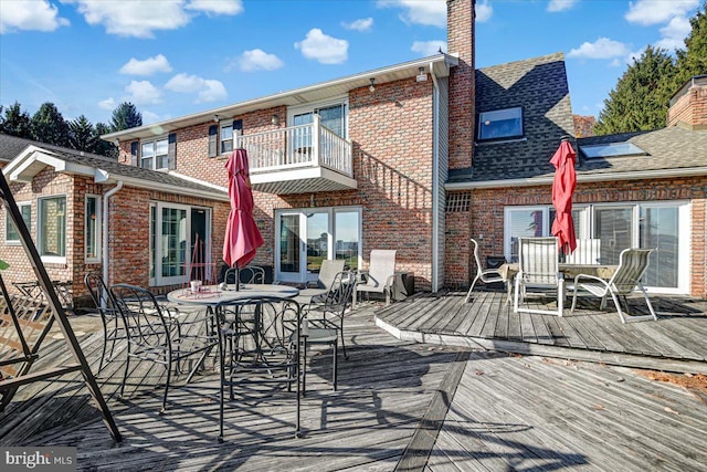 back of property featuring a balcony and a wooden deck