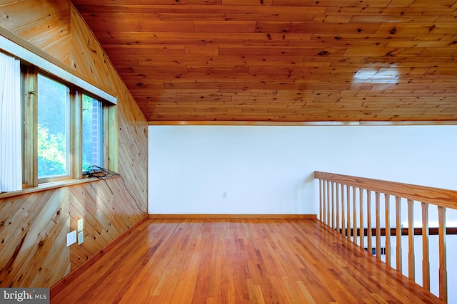 additional living space with lofted ceiling, light hardwood / wood-style floors, wooden ceiling, and wood walls