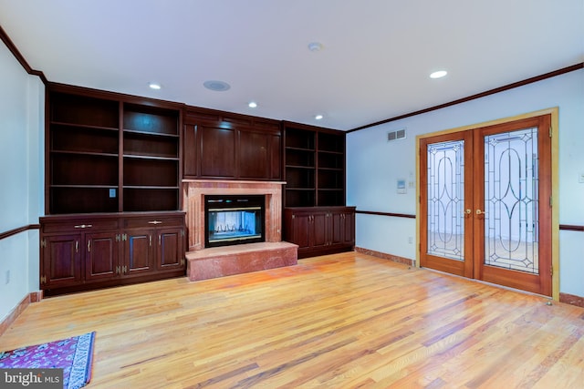 unfurnished living room with french doors, light hardwood / wood-style floors, crown molding, and built in features