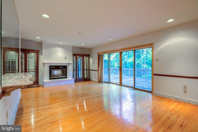 unfurnished living room featuring light wood-type flooring and a high end fireplace