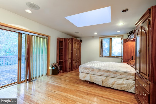 bedroom featuring light hardwood / wood-style flooring, access to exterior, and a skylight