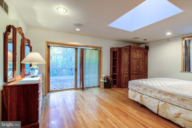 bedroom with light hardwood / wood-style flooring, a skylight, and access to exterior