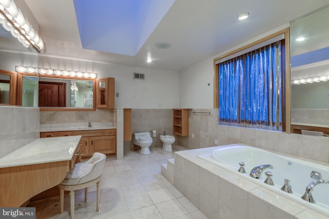 bathroom featuring tile patterned floors, toilet, a bidet, a relaxing tiled tub, and vanity