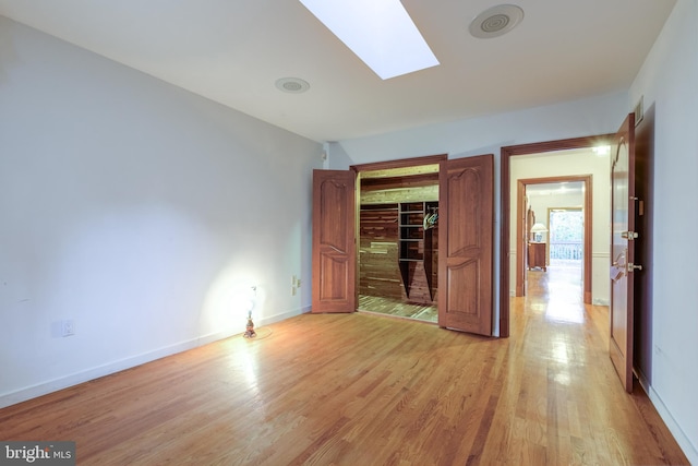 unfurnished bedroom featuring light hardwood / wood-style floors and a skylight