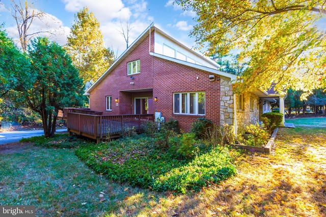 rear view of property featuring a wooden deck and a lawn