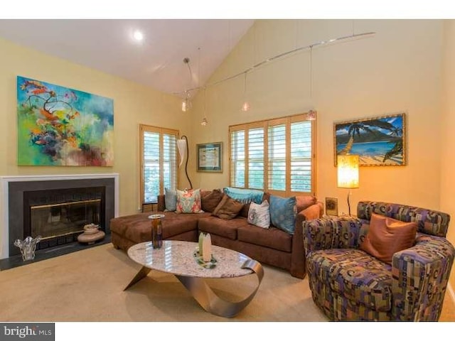 living room with light colored carpet, a healthy amount of sunlight, and high vaulted ceiling