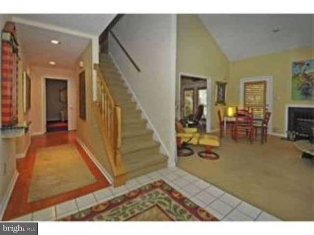 foyer entrance with light tile patterned floors, lofted ceiling, and a fireplace