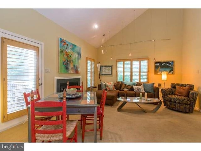 carpeted dining room featuring high vaulted ceiling