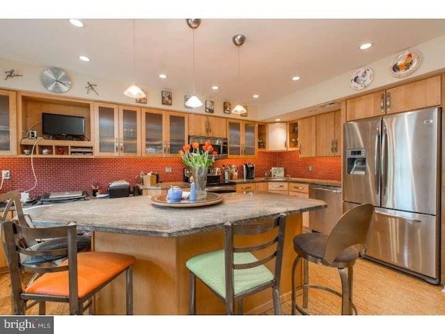 kitchen featuring backsplash, a breakfast bar area, light stone countertops, stainless steel appliances, and decorative light fixtures