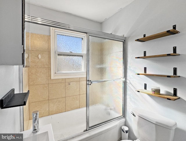 bathroom with combined bath / shower with glass door and toilet