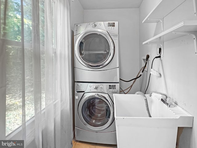 clothes washing area featuring sink, stacked washer / dryer, and light tile patterned floors