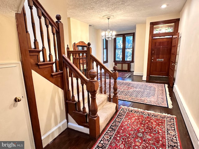 foyer entrance featuring a notable chandelier, dark hardwood / wood-style floors, a textured ceiling, and a baseboard heating unit