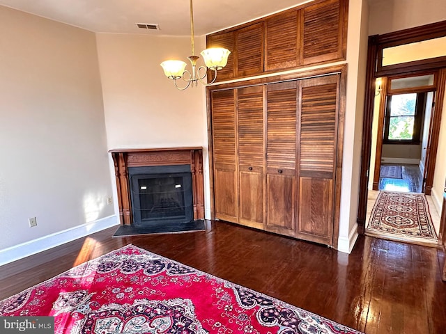 unfurnished living room with a chandelier, dark wood-style flooring, a fireplace, baseboards, and visible vents