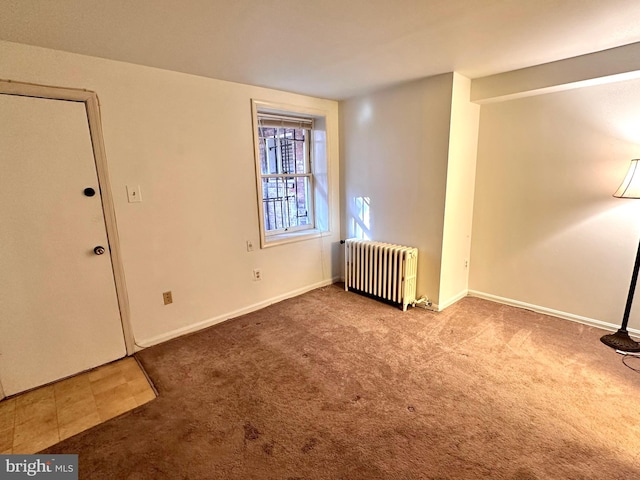 carpeted empty room with radiator heating unit and baseboards