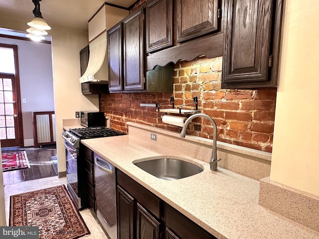 kitchen featuring light stone countertops, sink, light hardwood / wood-style floors, stainless steel appliances, and decorative light fixtures