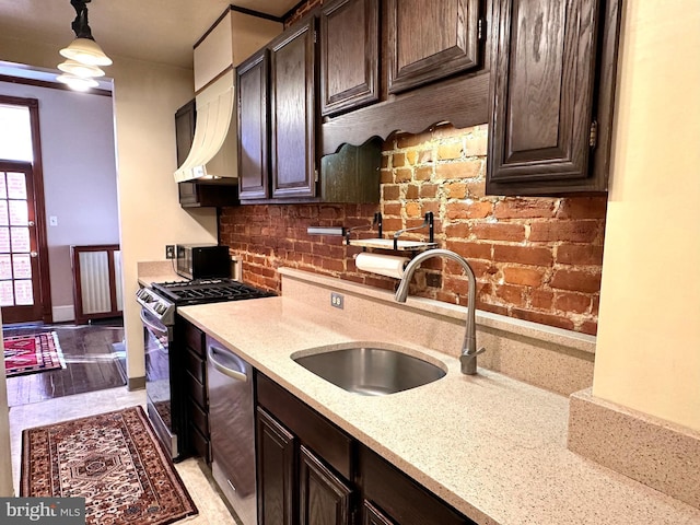 kitchen featuring a sink, stainless steel appliances, dark brown cabinetry, light stone counters, and backsplash