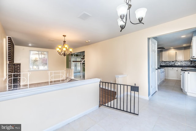 hall featuring a notable chandelier and light tile patterned floors