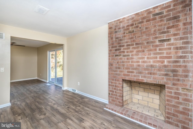 unfurnished living room featuring hardwood / wood-style flooring and a brick fireplace