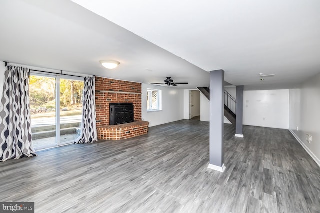 unfurnished living room featuring a brick fireplace, hardwood / wood-style floors, ceiling fan, and a wealth of natural light