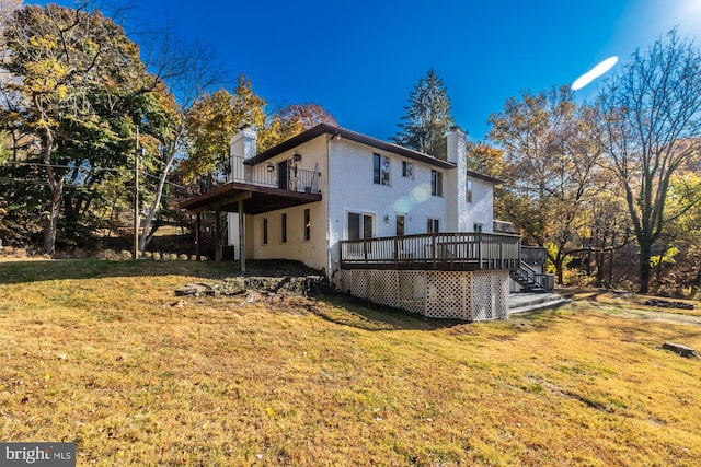 back of property featuring a deck and a lawn