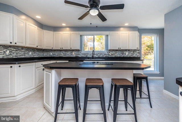 kitchen with a breakfast bar area, a center island, white cabinetry, and backsplash